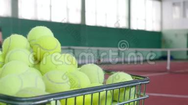 两个年轻人在网球场上打网球。 培训。 一辆摆满网球的手推车